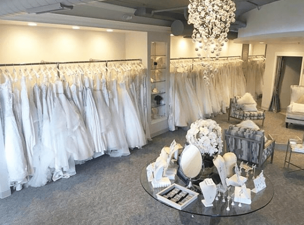 shows inside of White Dress with accessories and row of Bridal Gowns in background