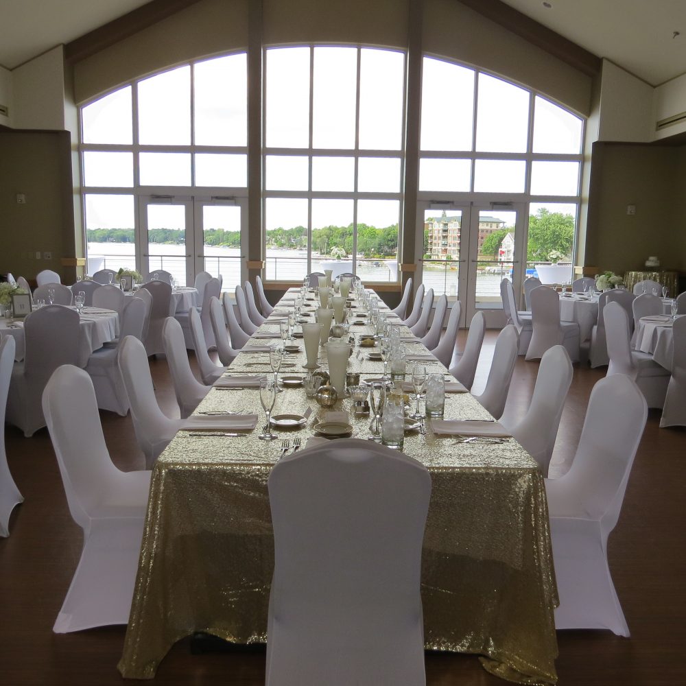 Wedding reception head with white fitted chair covers overlooking Lac La Belle at the The Oconomowoc Community Center