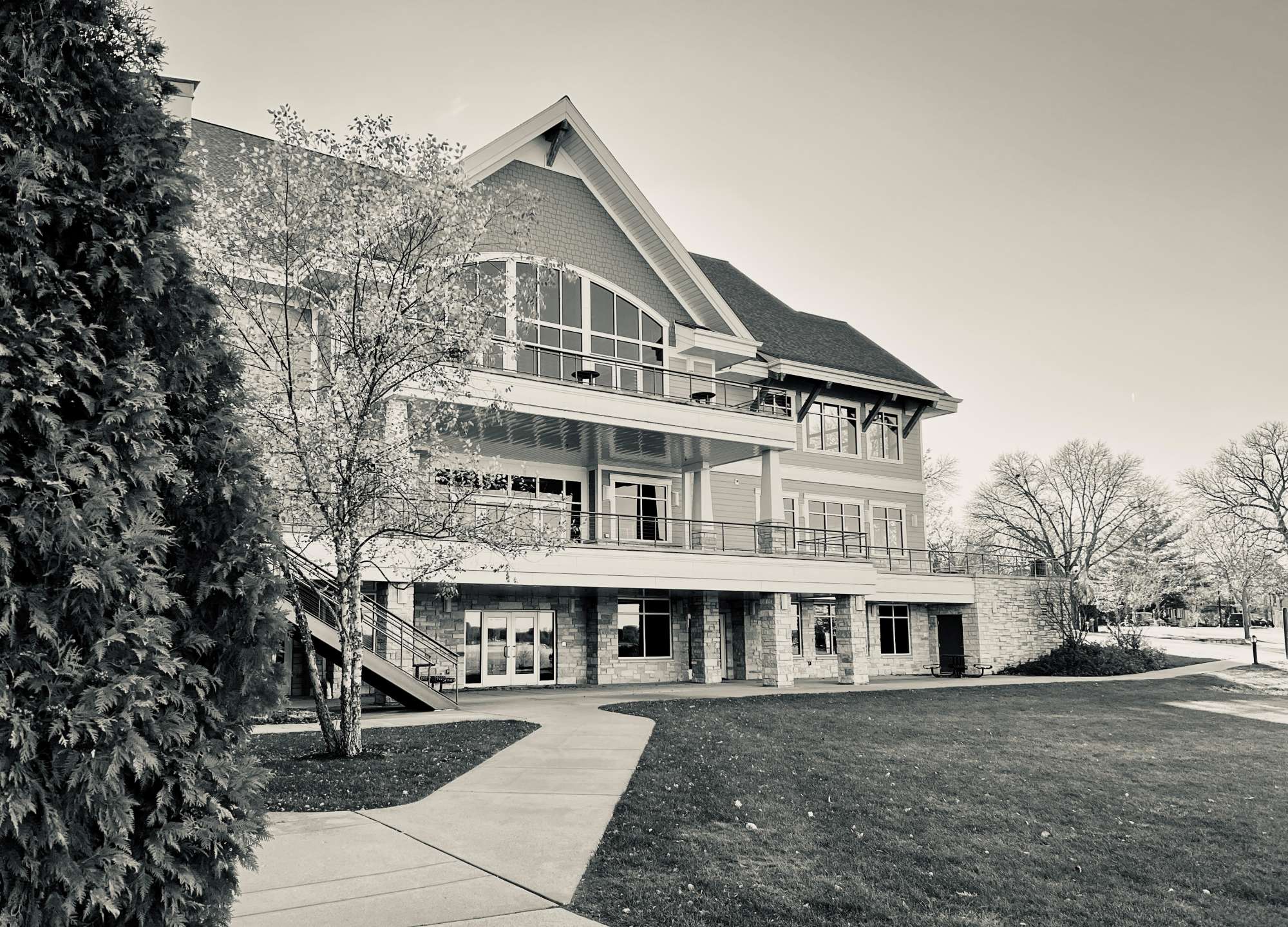 Black and white exterior view of Oconomowoc Community Center, a multi-story event venue with large windows and balconies.