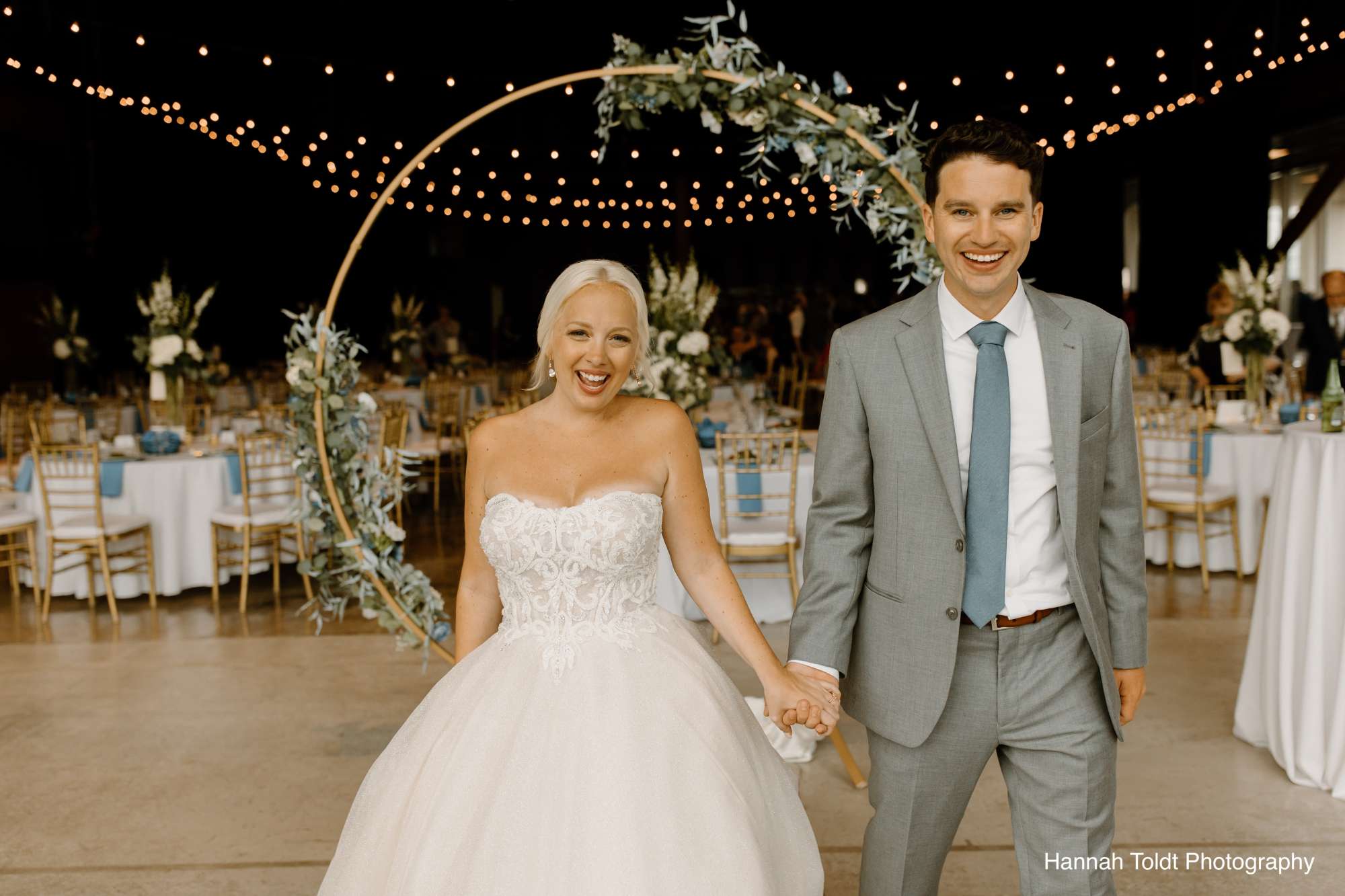 Guests seated at elegantly set tables adorned with lush floral arrangements under warm string lights at Jan Serr Studio.