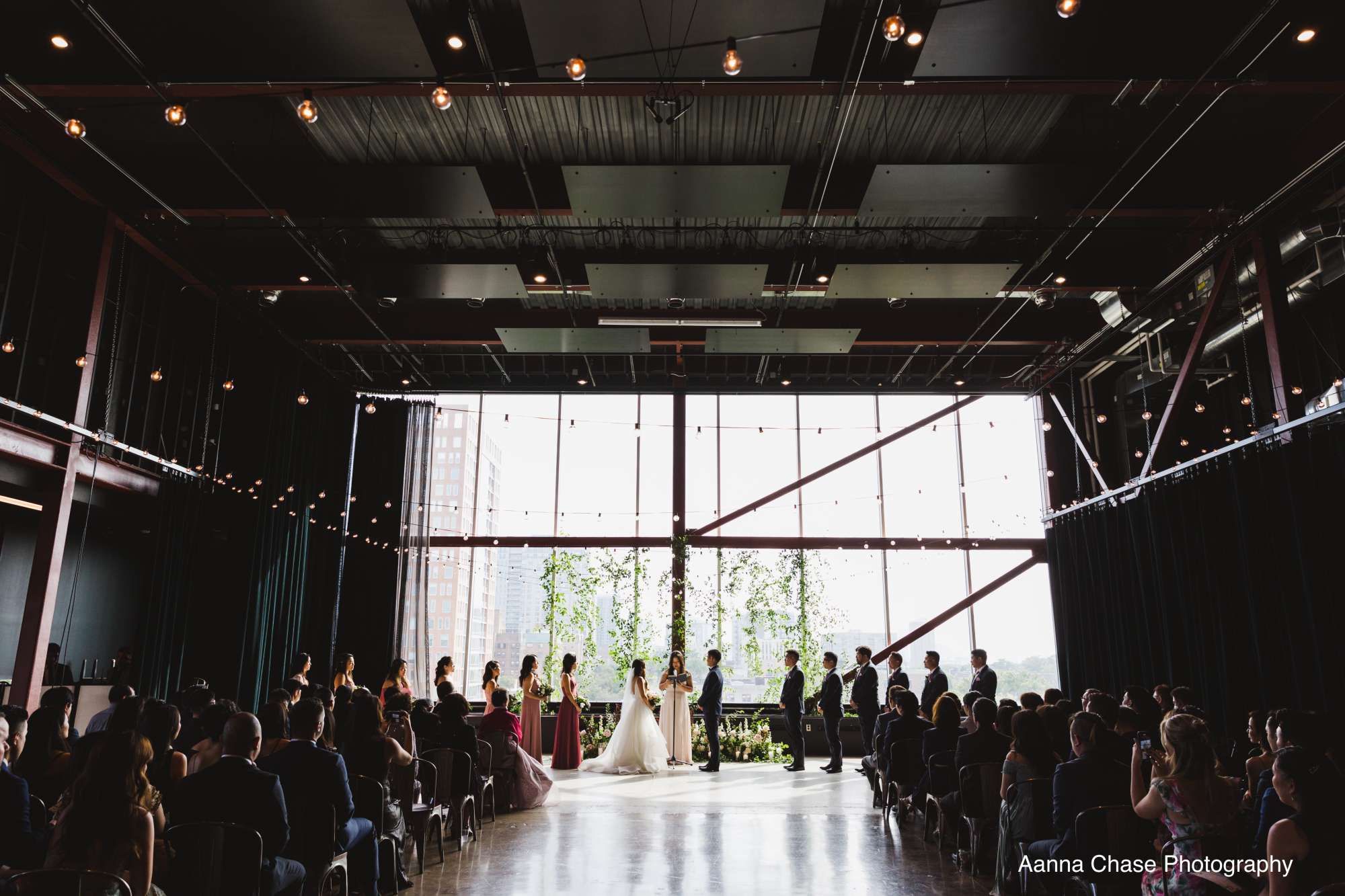 Guests witness a heartfelt wedding ceremony framed by the industrial-chic architecture of Jan Serr Studio.