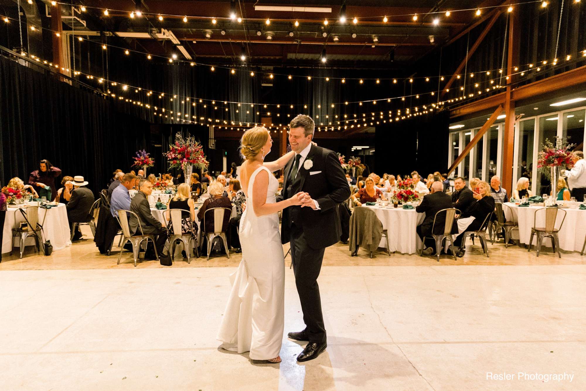 Bride and groom enjoy dancing beneath twinkling bistro lights on the dance floor at Jan Serr Studio.