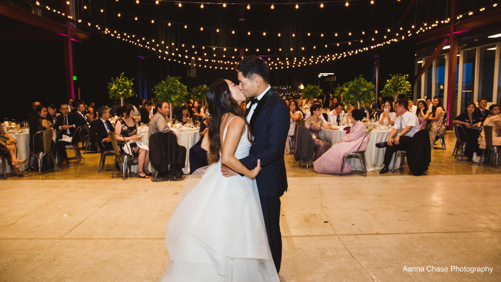 A couple sharing their romantic first dance under enchanting bistro lights in Jann Serr Studio.