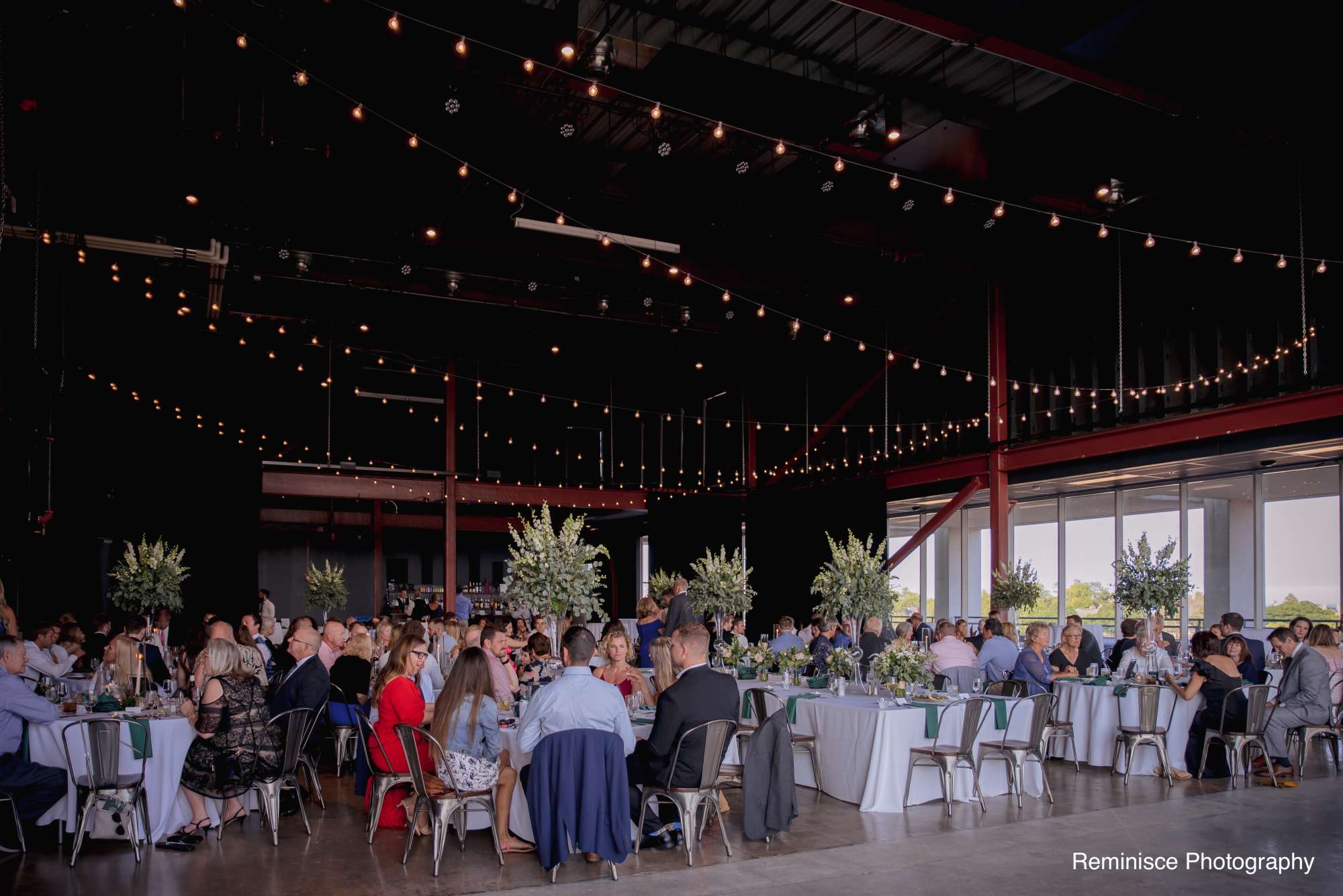 Guests enjoying a lively reception with beautifully arranged dining tables and soft overhead lighting.