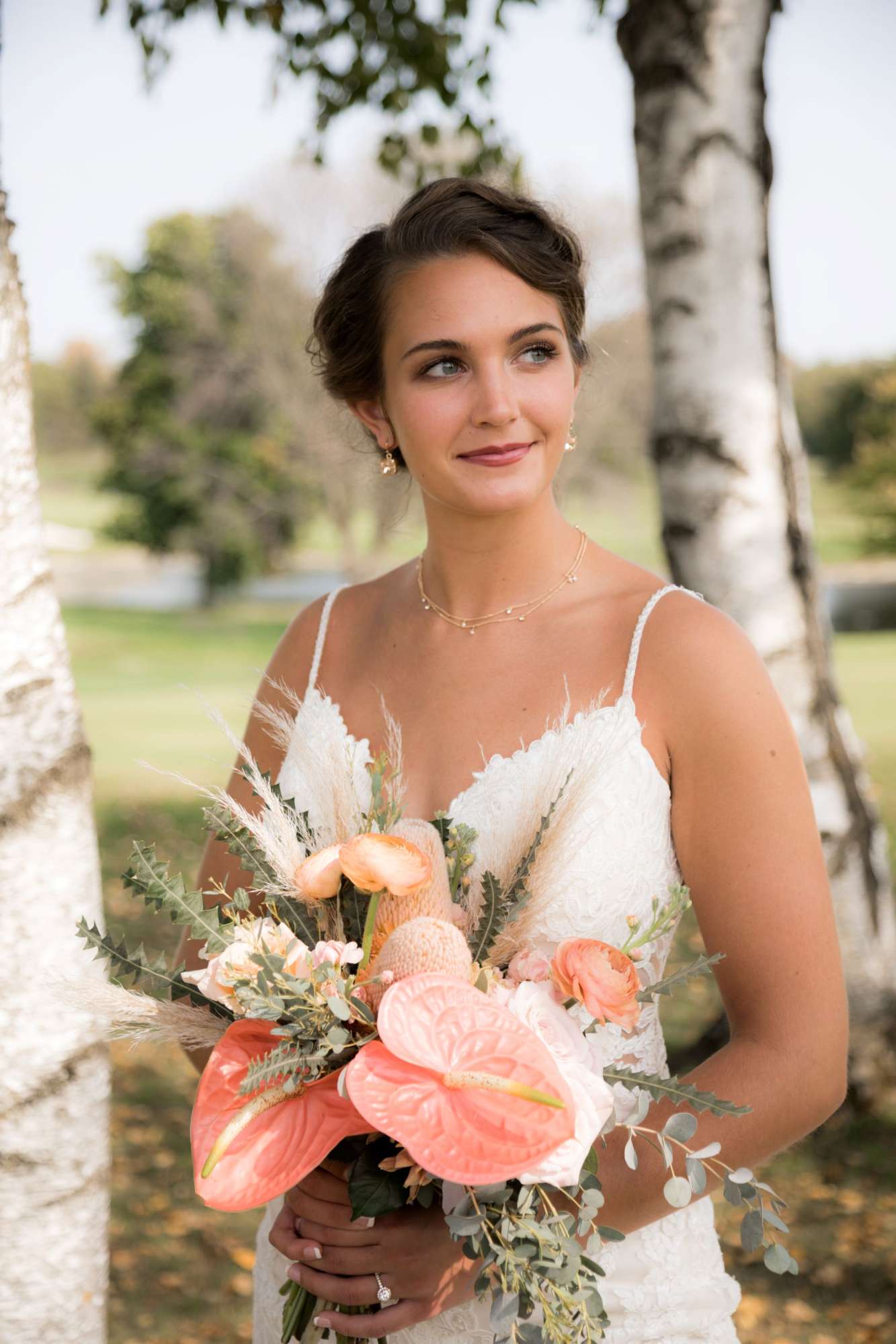 A beautiful bride holds a unique Ambrosia Events bouquet with coral anthuriums, pampas grass, and lush greenery for a boho-chic wedding style.