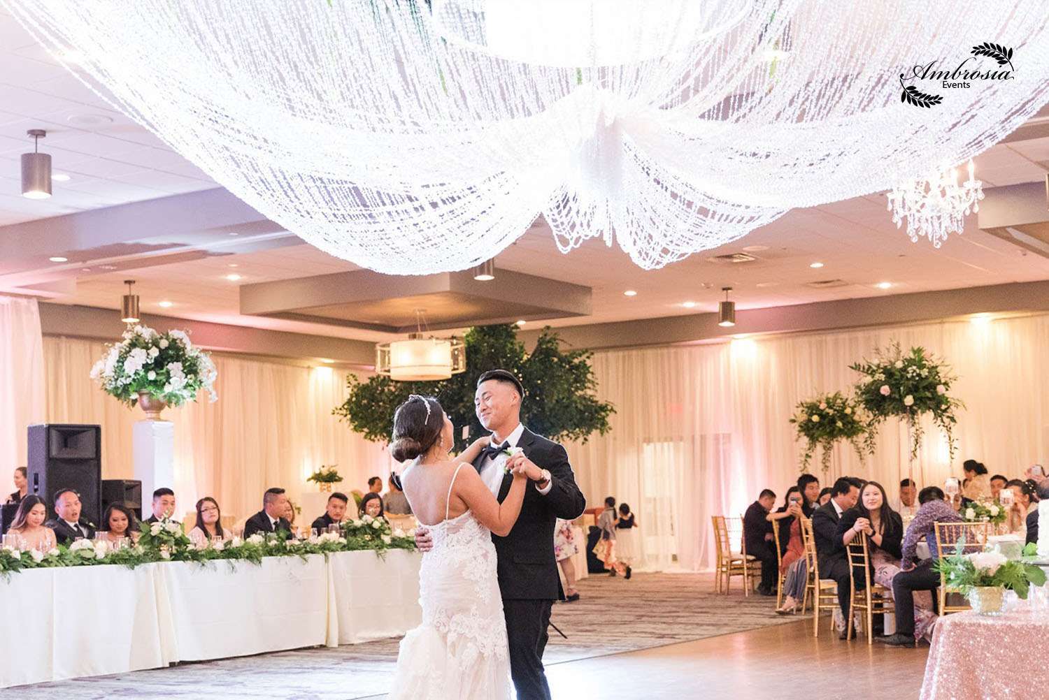 Under a stunning crystal chandelier, Ambrosia Events creates a dreamy reception setting for the couple’s first dance.