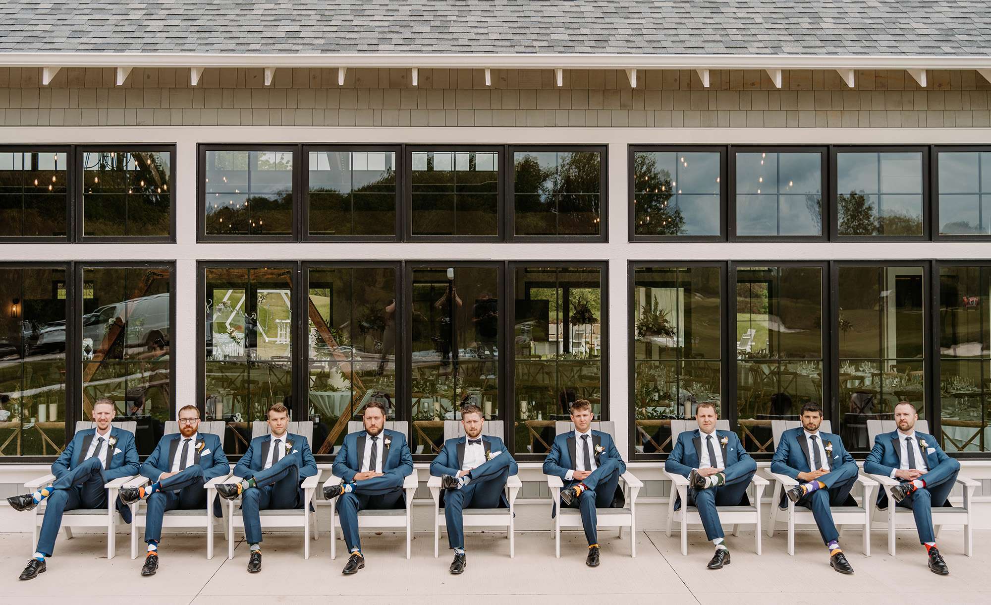 Groom and groomsmen sit in row of lawn chairs at The Carriage House at the Club at Lac La Belle.