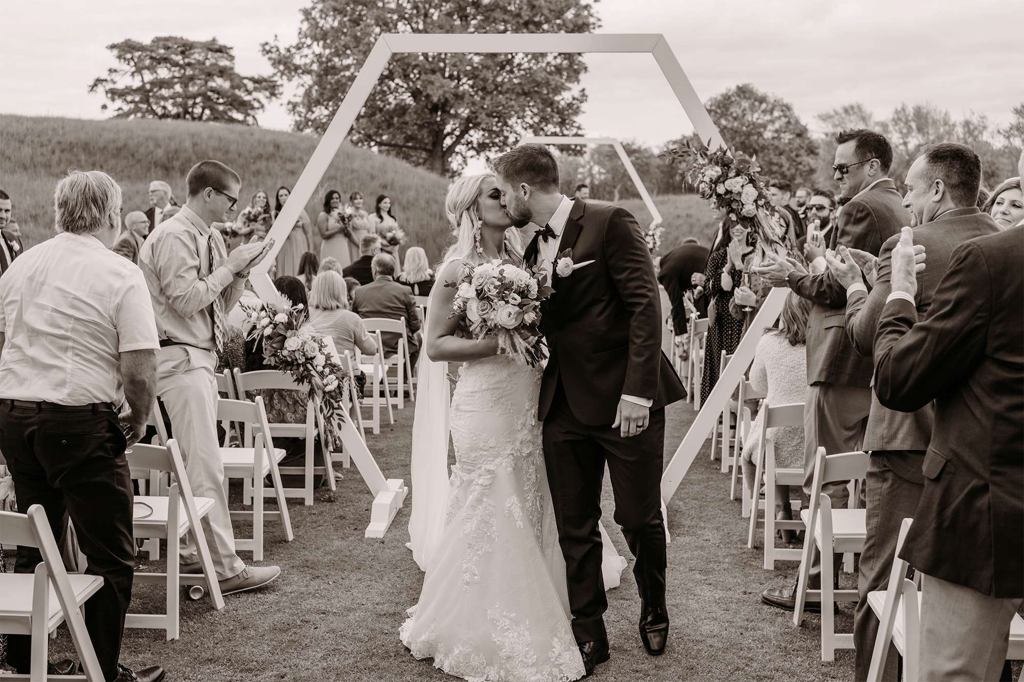 Bride and groom kiss on their way back up the aisle at outdoor ceremony at The Carriage House at the Club at Lac La Belle.