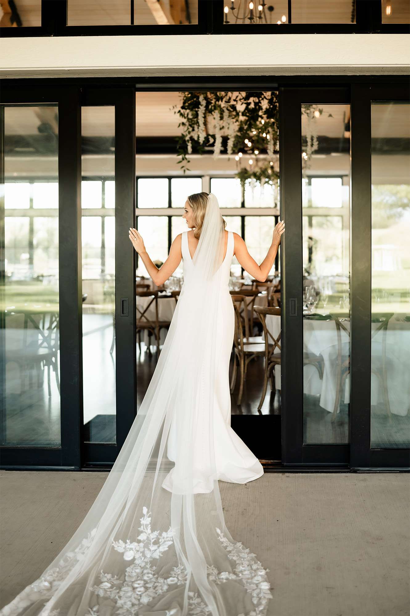 Bride poses at doors of the Carriage House at the Club at Lac La Belle