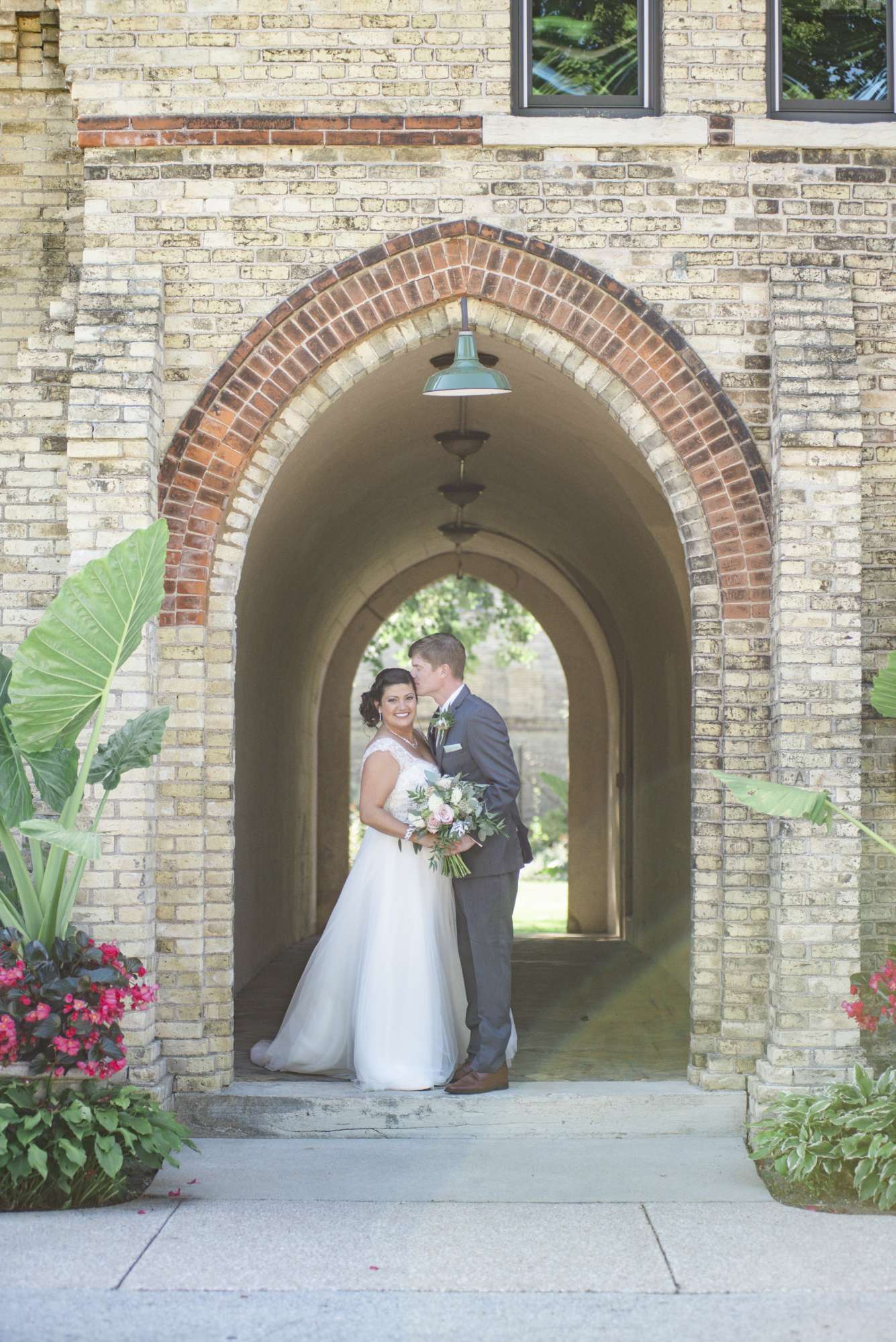 Wedding couple pose under brick arch