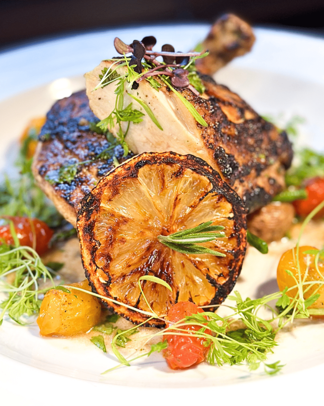 Noble Catering’s grilled chicken entrée is served with blistered tomatoes, fresh herbs, and charred lemon for bold flavor.
