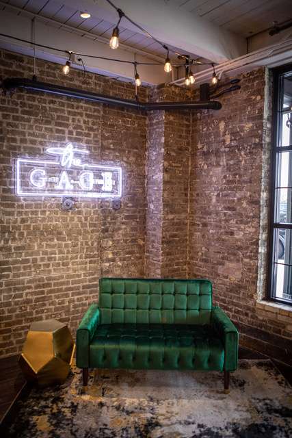 green vintage loveseat under the neon Gage sign