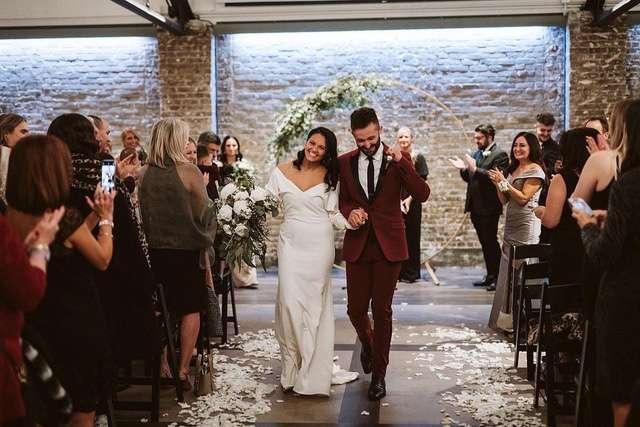 Bride and groom walk back up aisle after exchanging vows at the Gage in Milwaukee