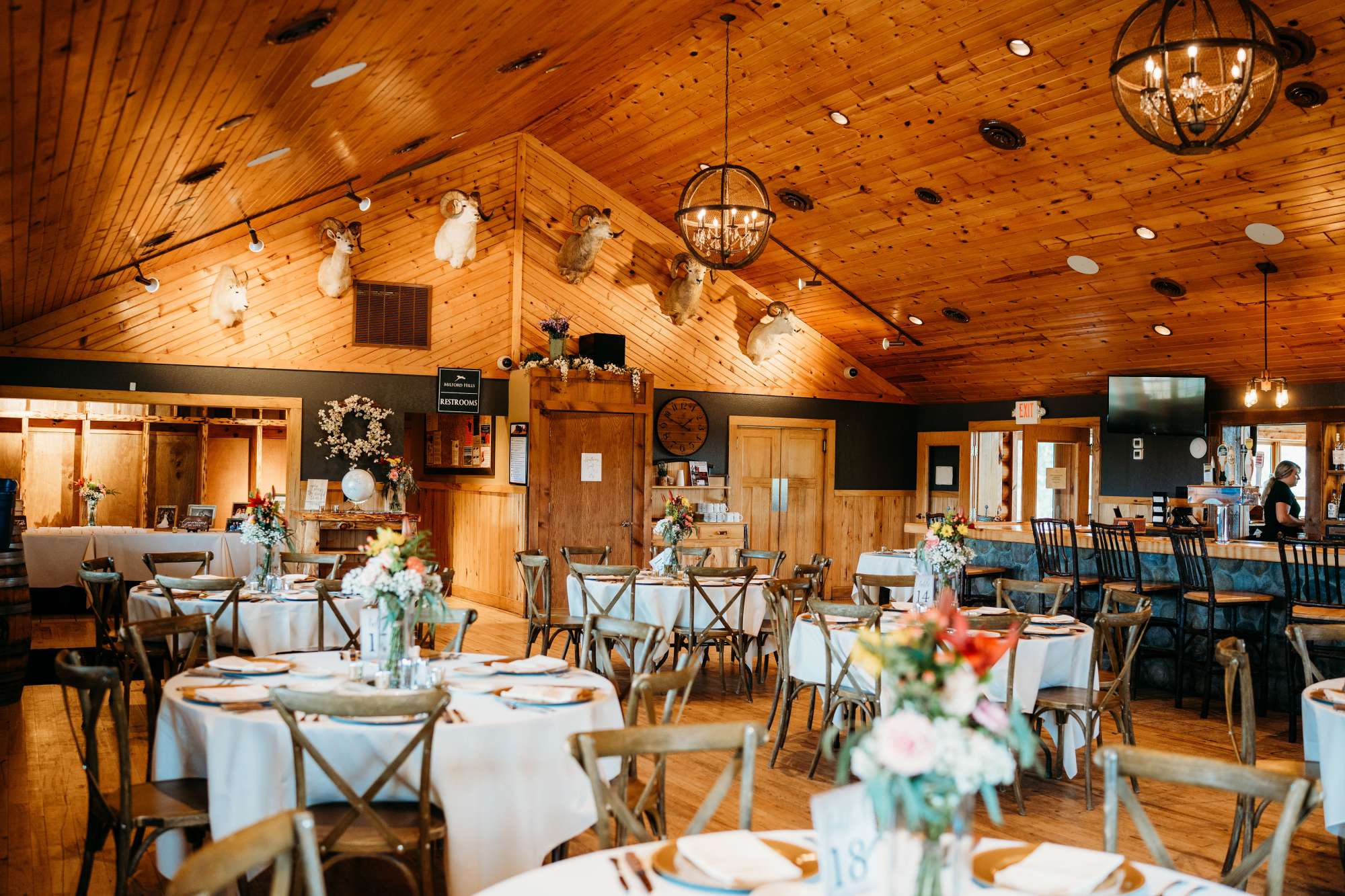 A beautifully decorated reception area at Milford Hills, featuring elegant floral centerpieces, wooden accents, and cozy lighting that enhances the venue’s rustic charm.