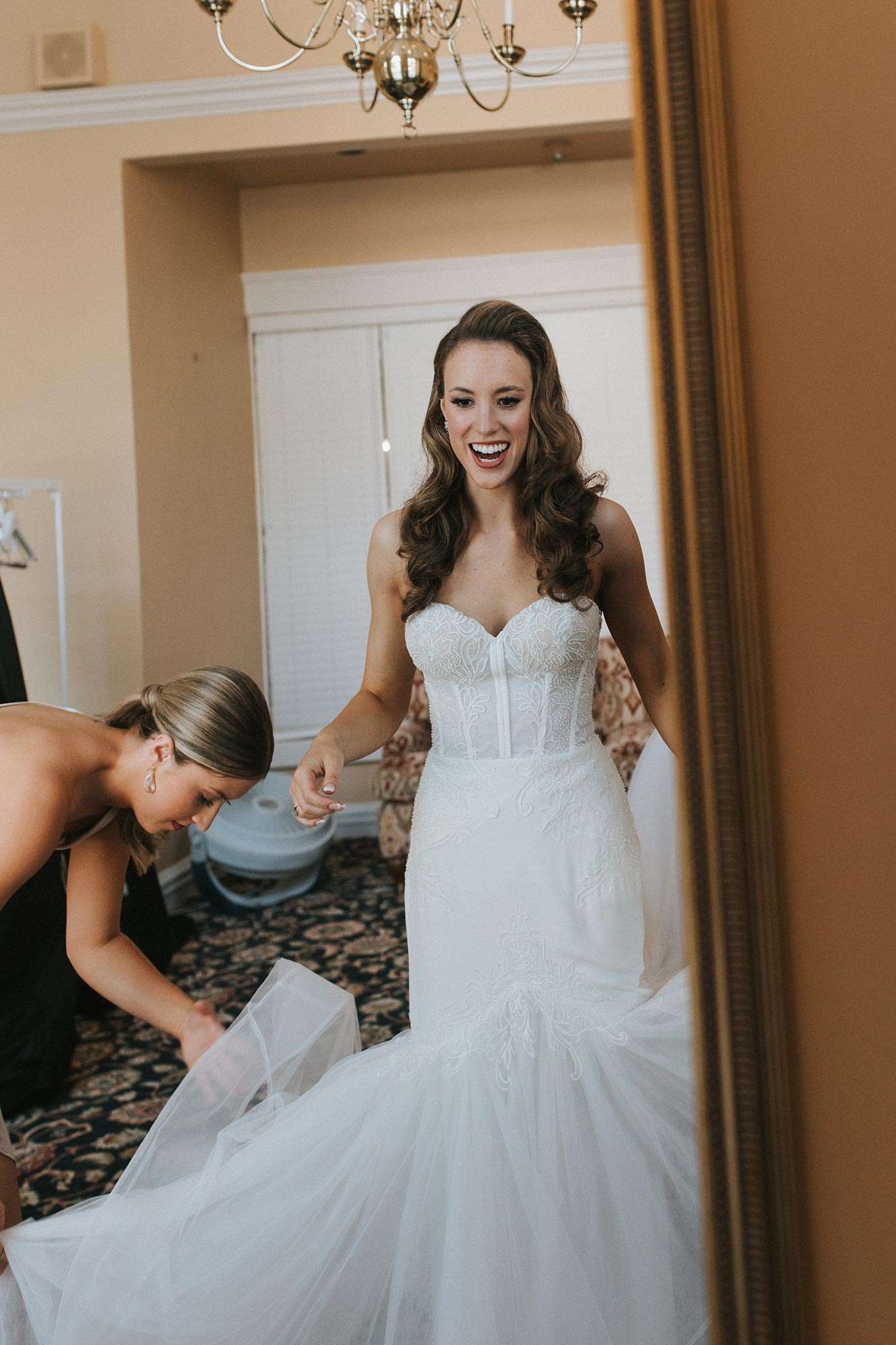Caroline looks into a mirror as her dress from Amelishan Bridal gets fluffed
