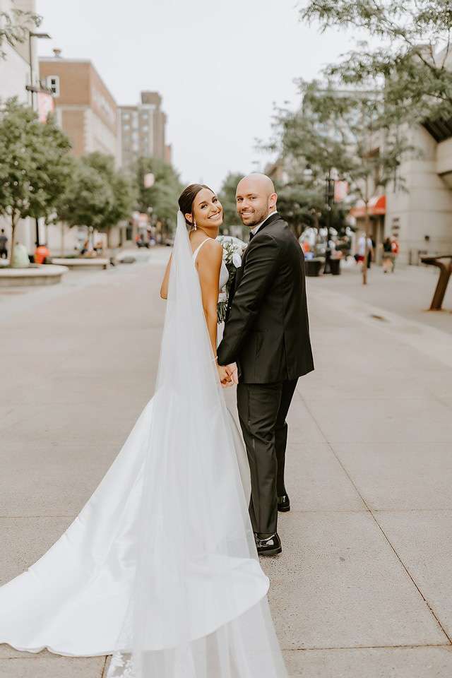Bride and groom pose in middle of city street.