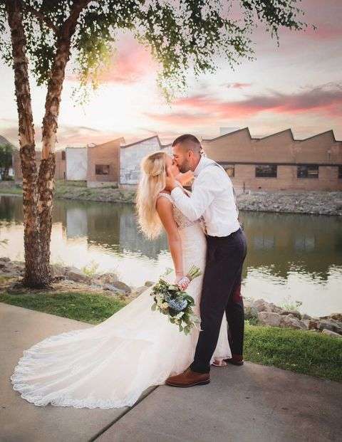 Groom kisses bride along the riverwalk in Beloit, WI