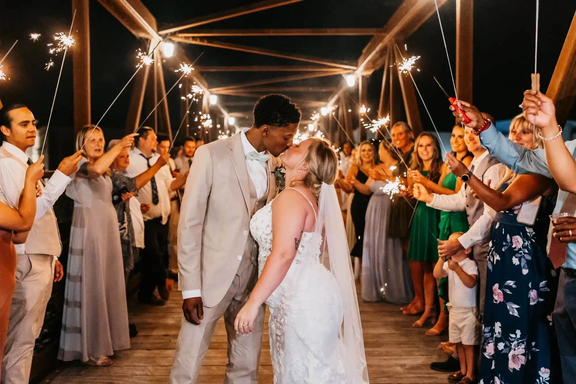 Bride and groom kiss with sparklers surrounding them from guests at Ironworks Hotel.