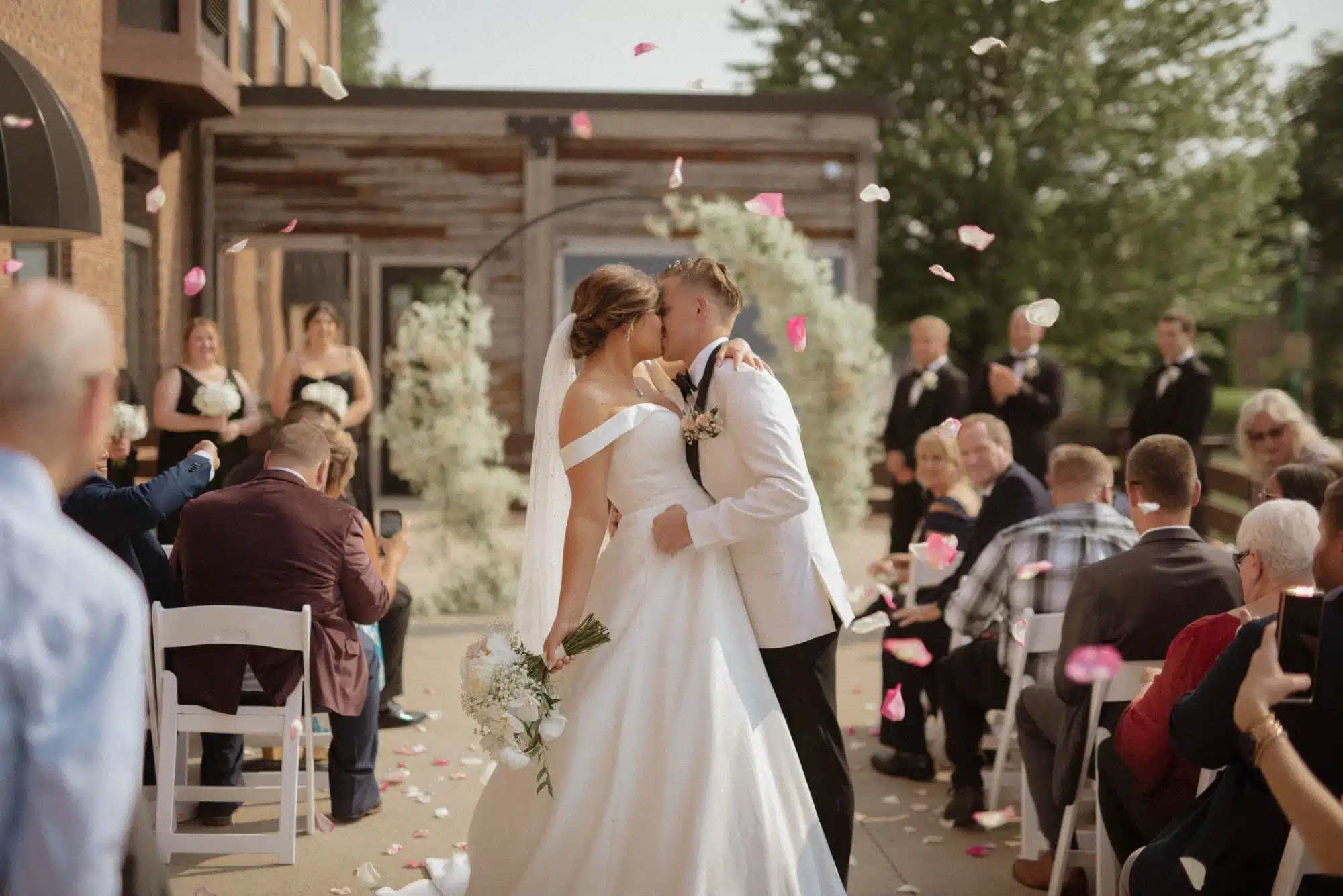Bride and groom kiss at wedding ceremony at outdoor space at Ironworks Hotel.