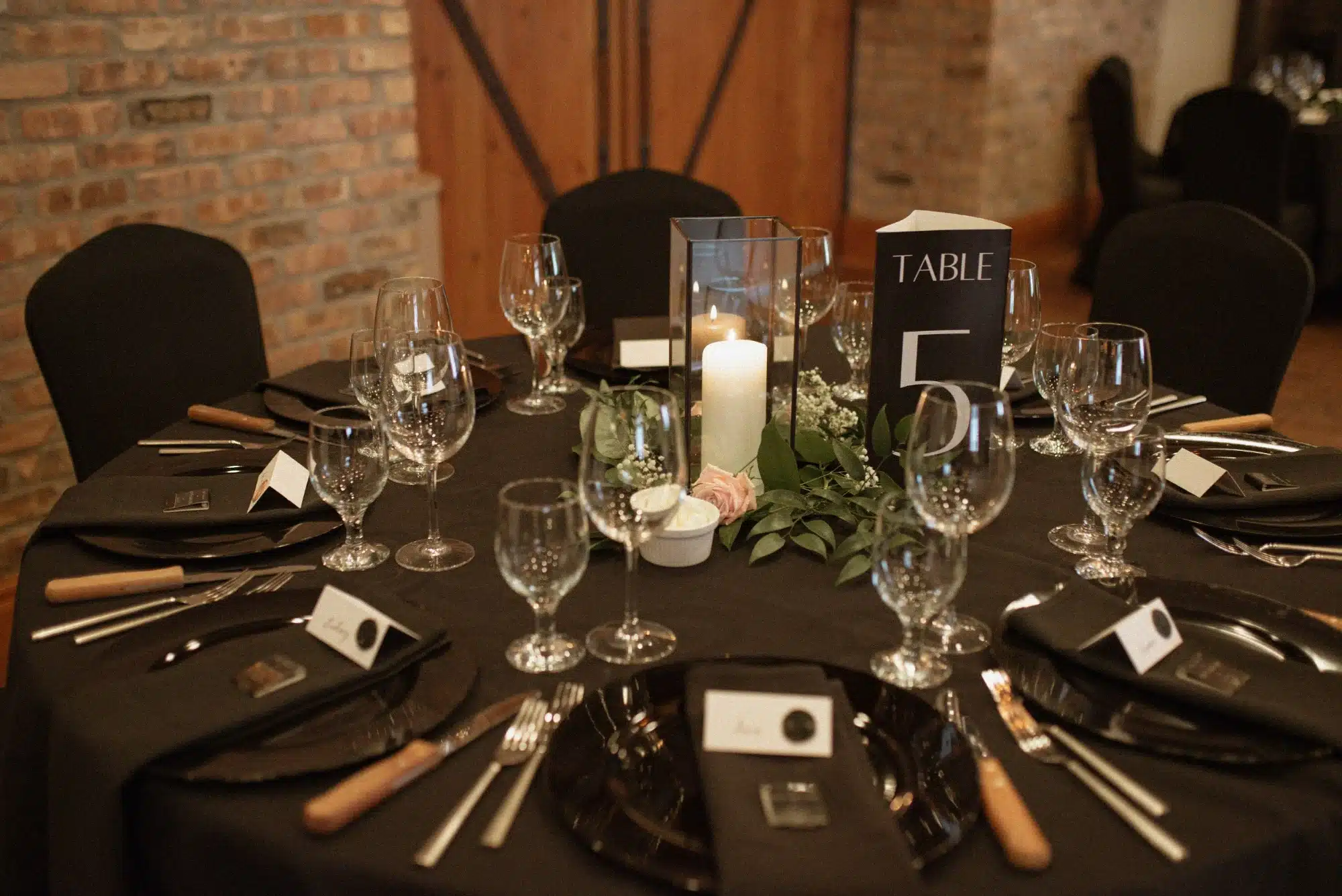 Ironworks hotel wedding decor, black tablecloth and greenery and candle centerpiece.