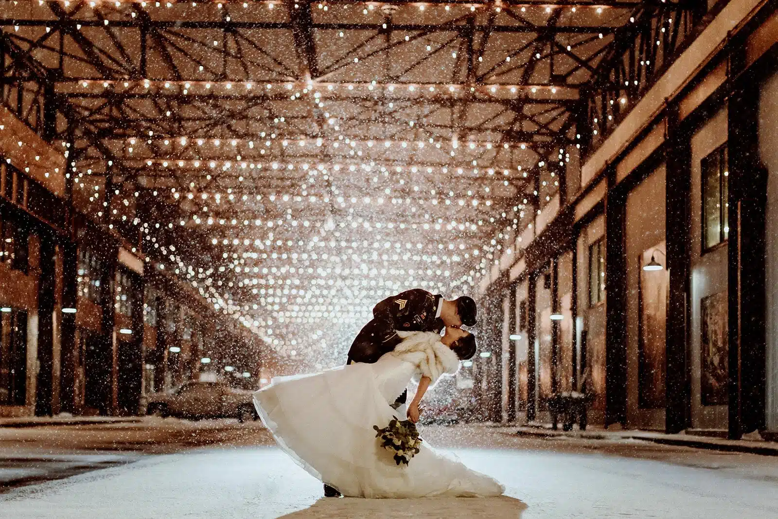 Groom dipping bride as it snows and they kiss at Ironworks Hotel Beloit.