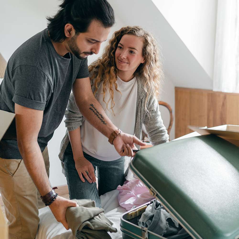 Woman helping man pack his suitcase
