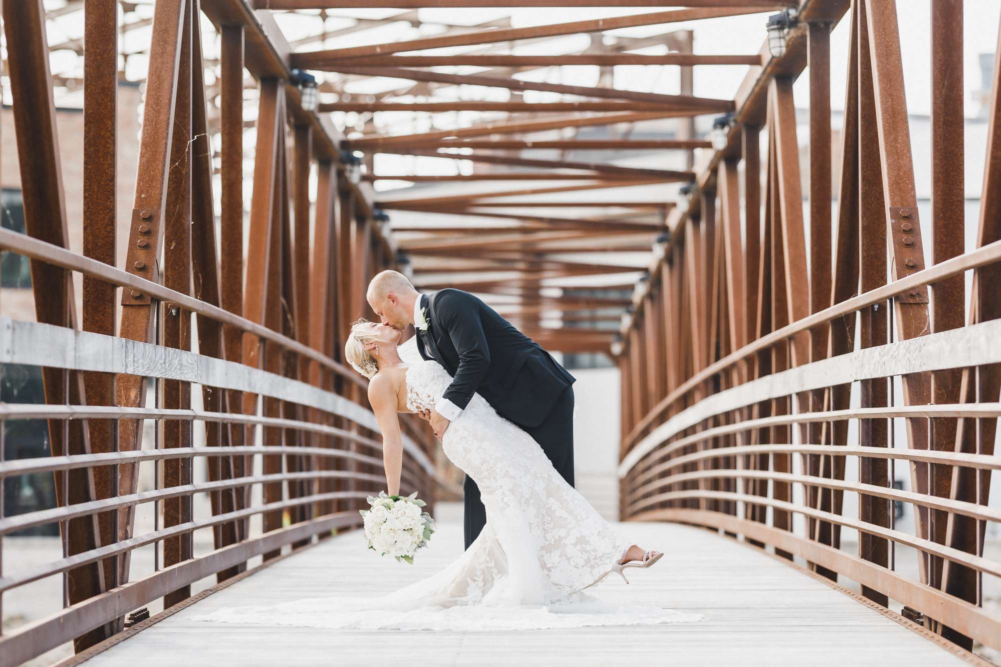 Bride and groom kiss on the Riverwalk Bridge-Ironworks Hotel Beloit