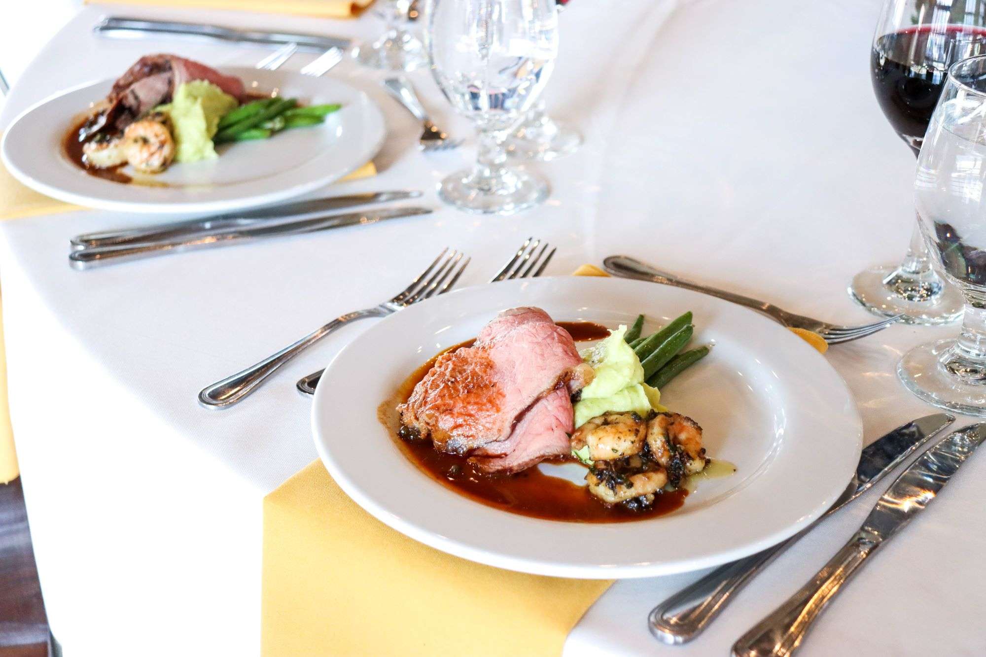 Steak and Shrimp Duet Grilled Sliced NY Strip Loin with Brandied Peppercorn Sauce and Roasted Garlic and Herb Jumbo Shrimp Served with Green Onion Pesto Mashed Potatoes and Green Beans