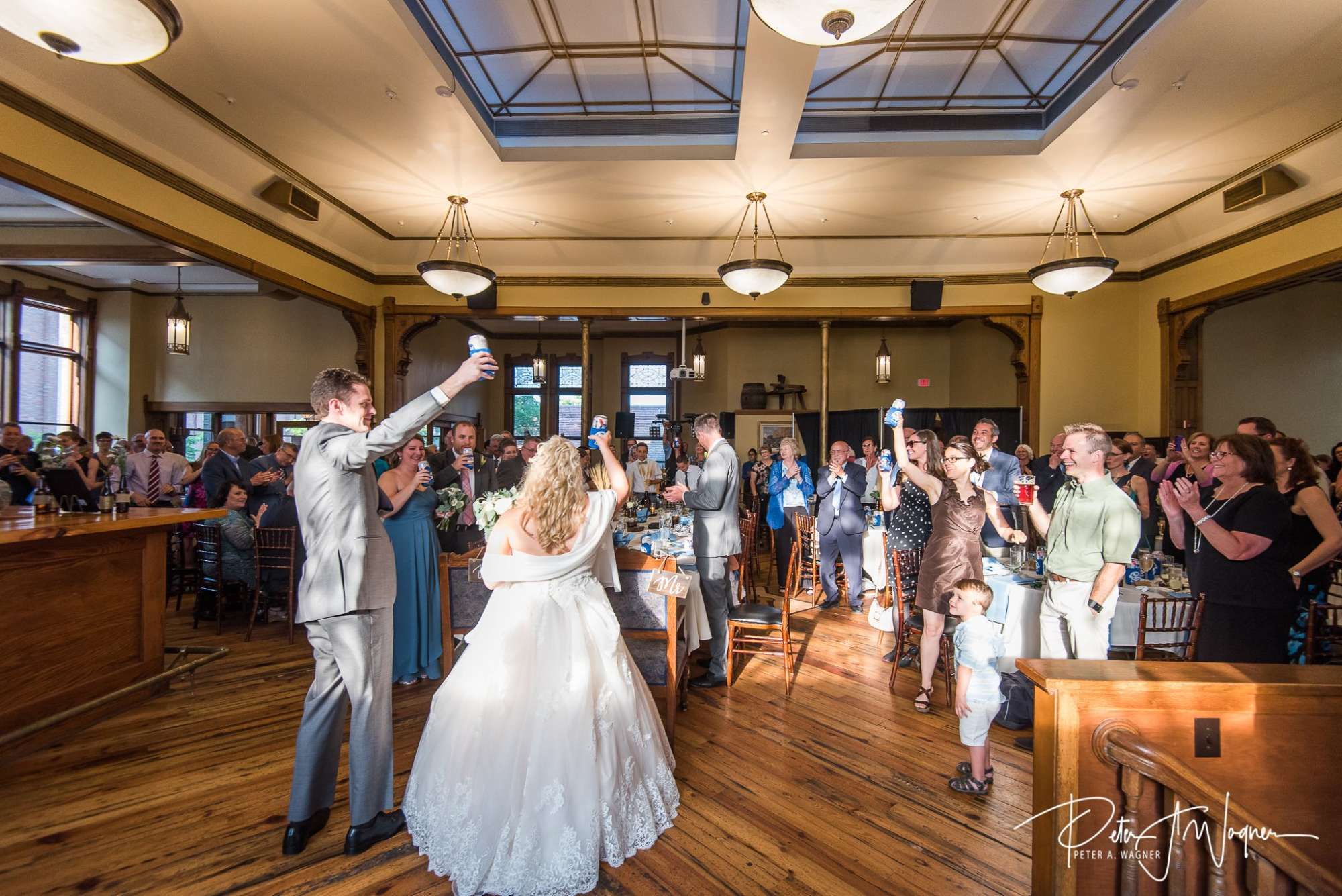 A newlywed couple raises a toast surrounded by cheering family and friends in The Great Hall at Best Place at Historic Pabst Brewery.