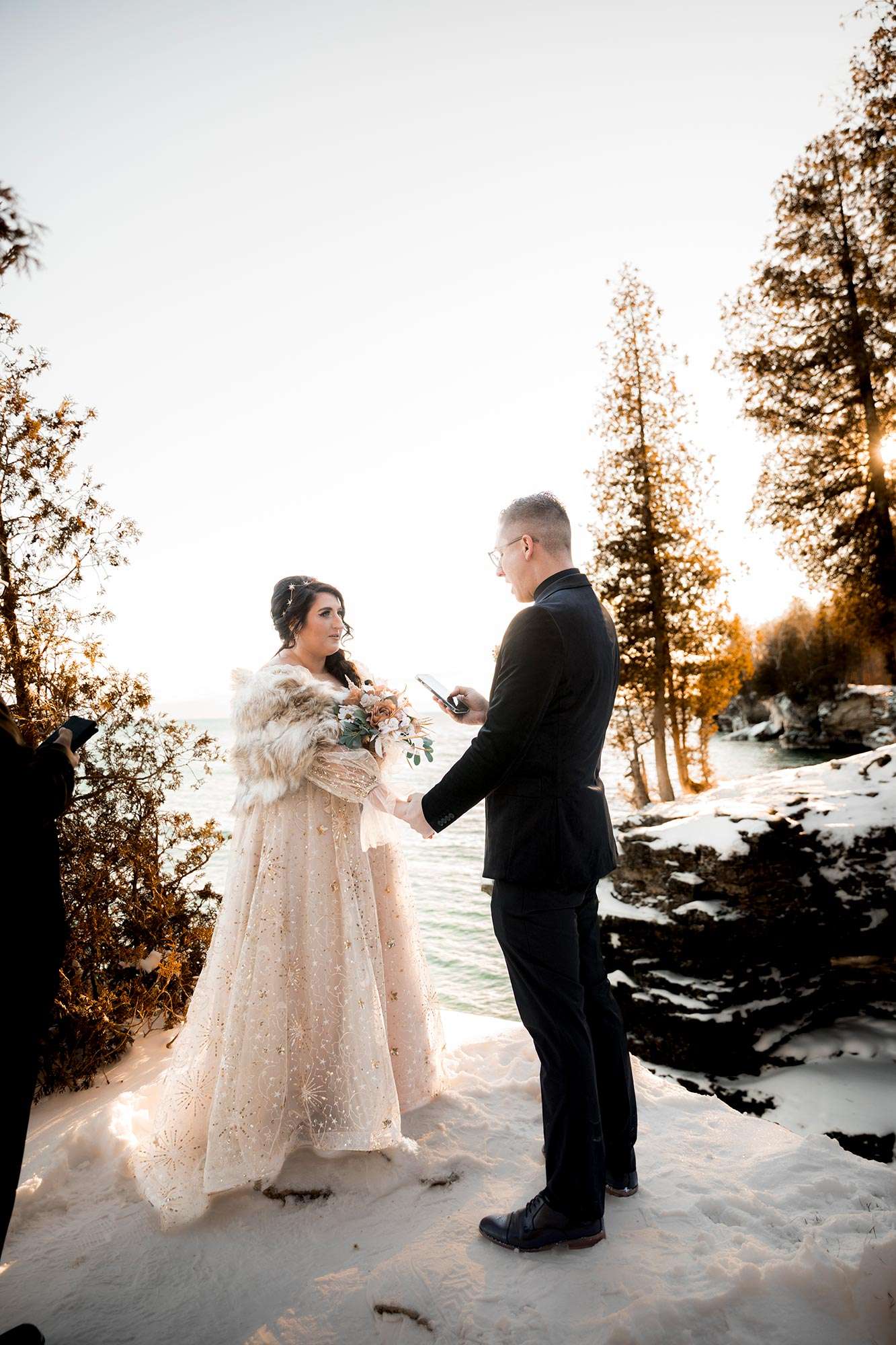 groom holding bride’s hand while reciting his vows from phone groom holding bride's hand while reciting his vows from phone