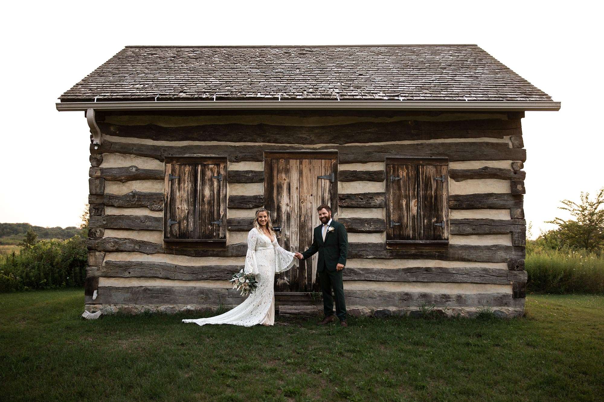 couple holding hands in front of wooden cabin couple holding hands in front of wooden cabin
