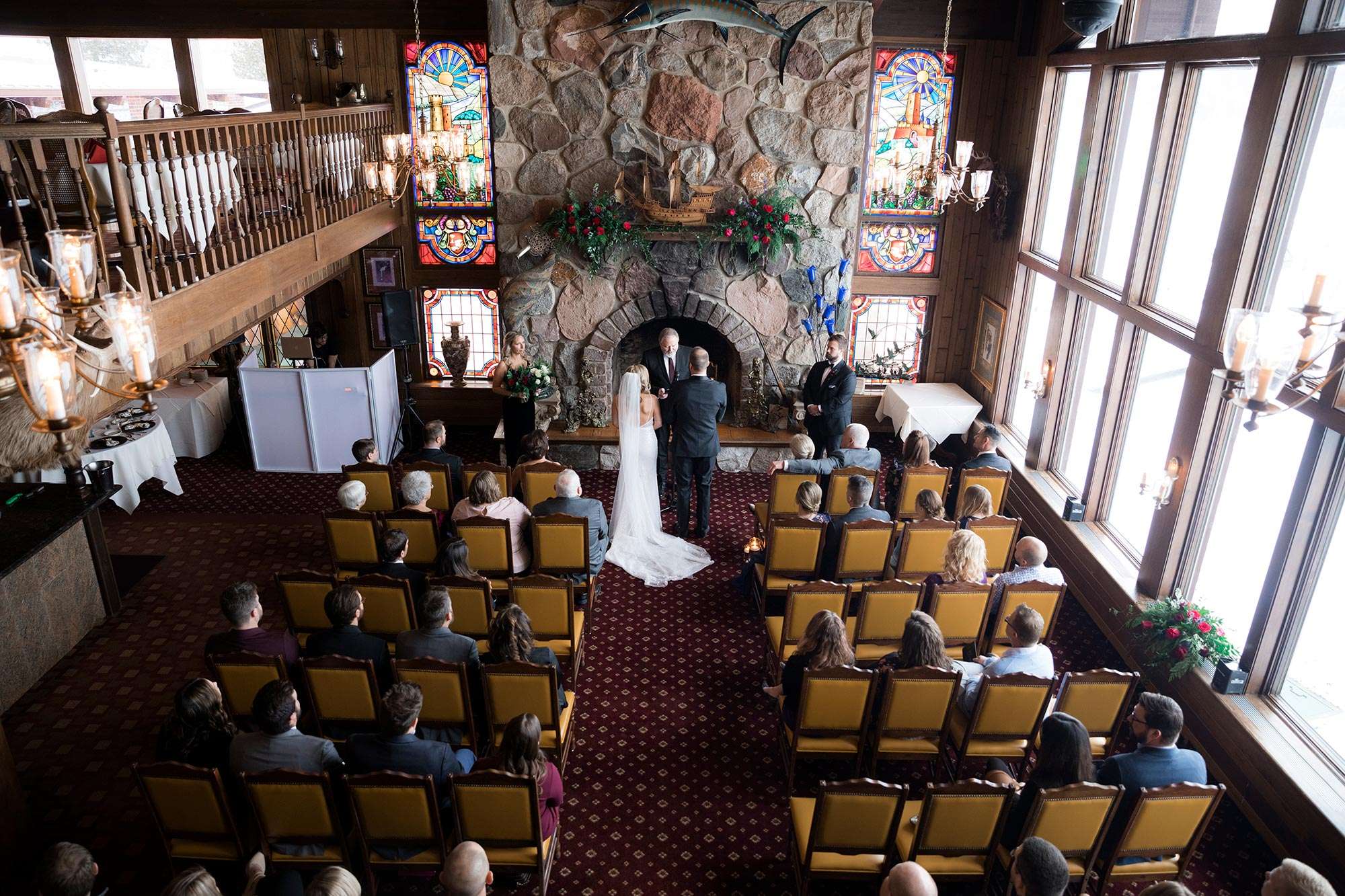 ceremony space from balcony above with stained glass windows on both sides of fireplace