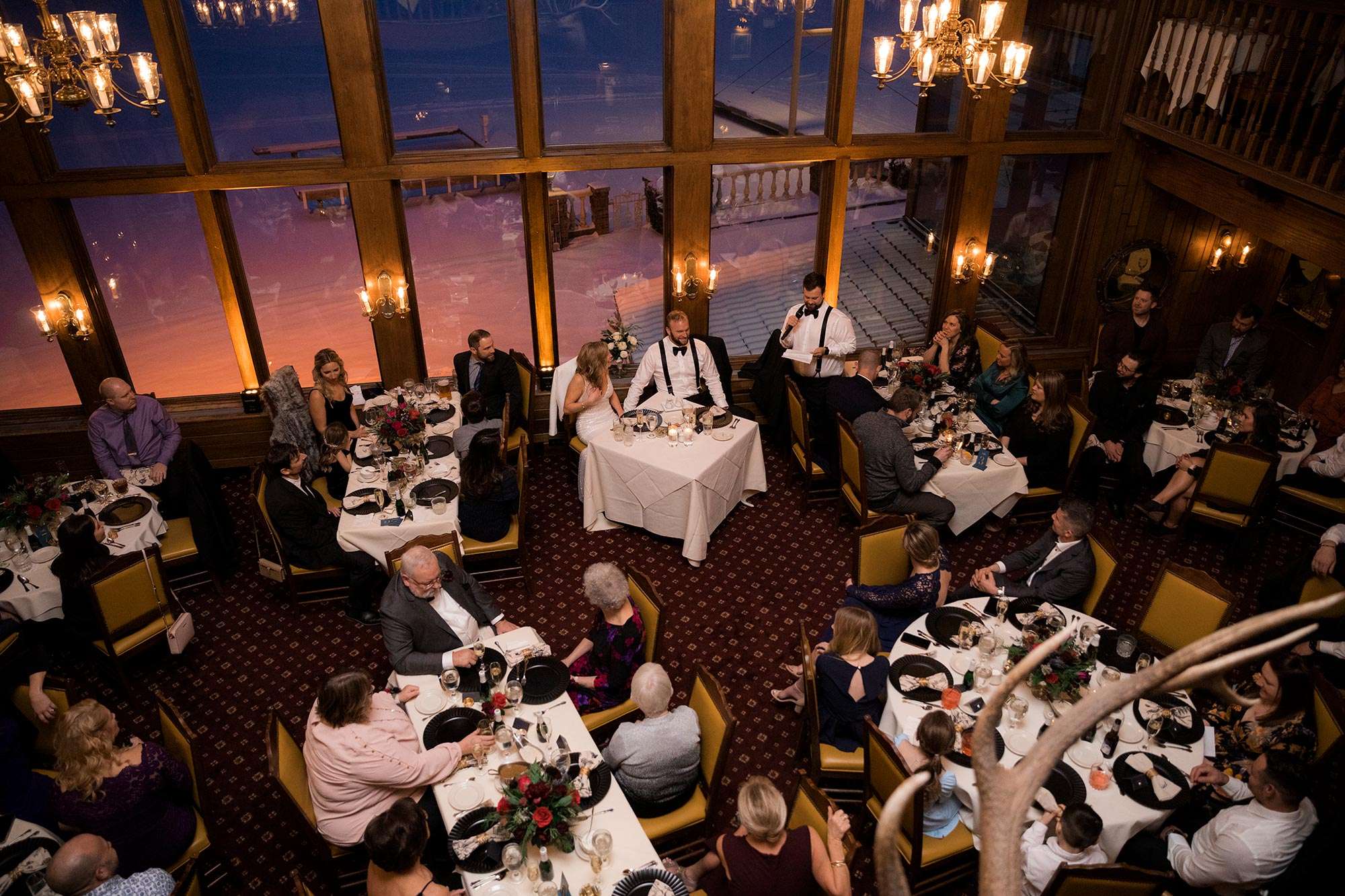 overhead view of guests seated at tables with soft glow of lights and floor to ceiling windows
