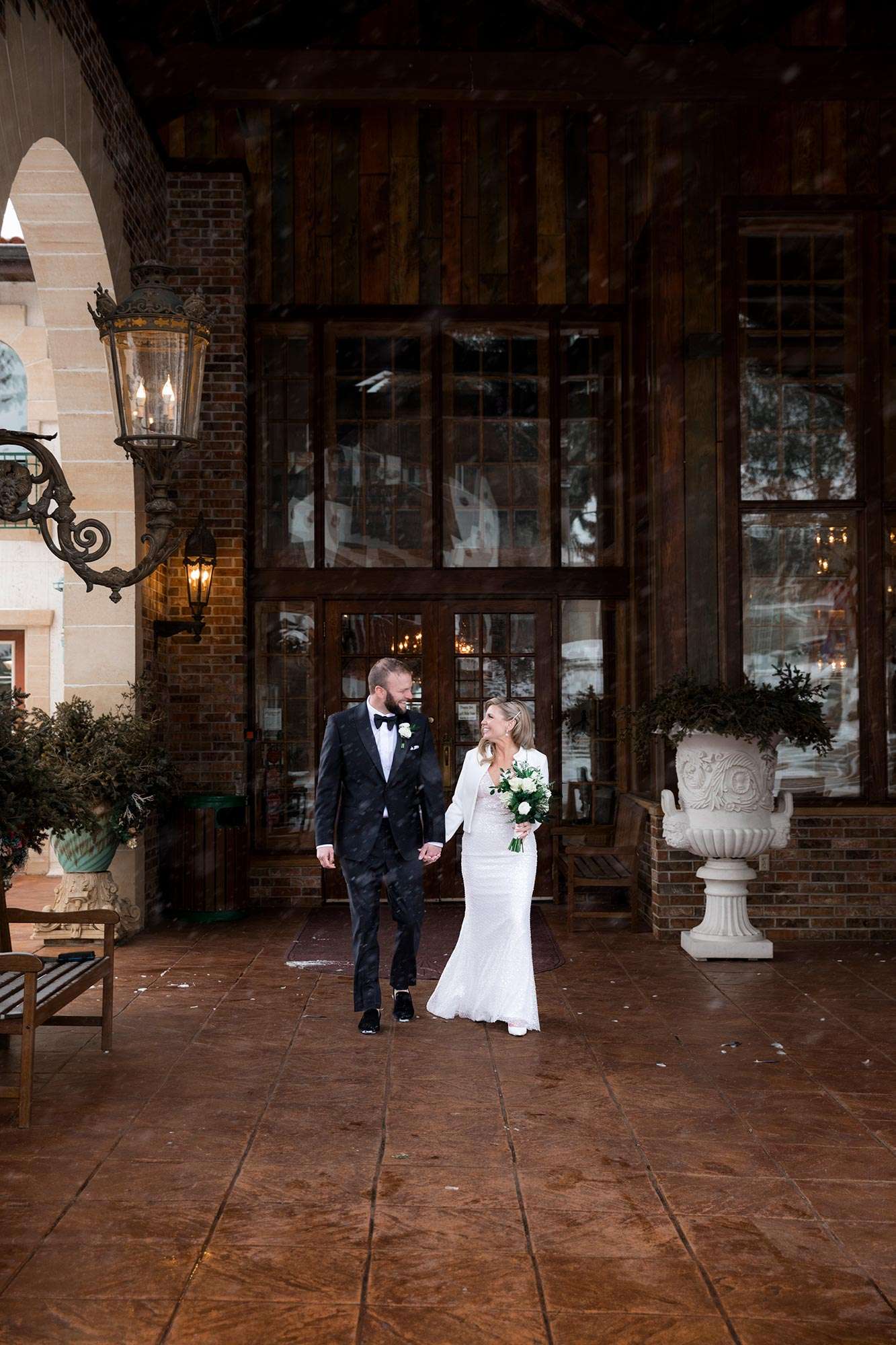 couple walking hand in hand outside Golden Mast rustic wood doors/decor