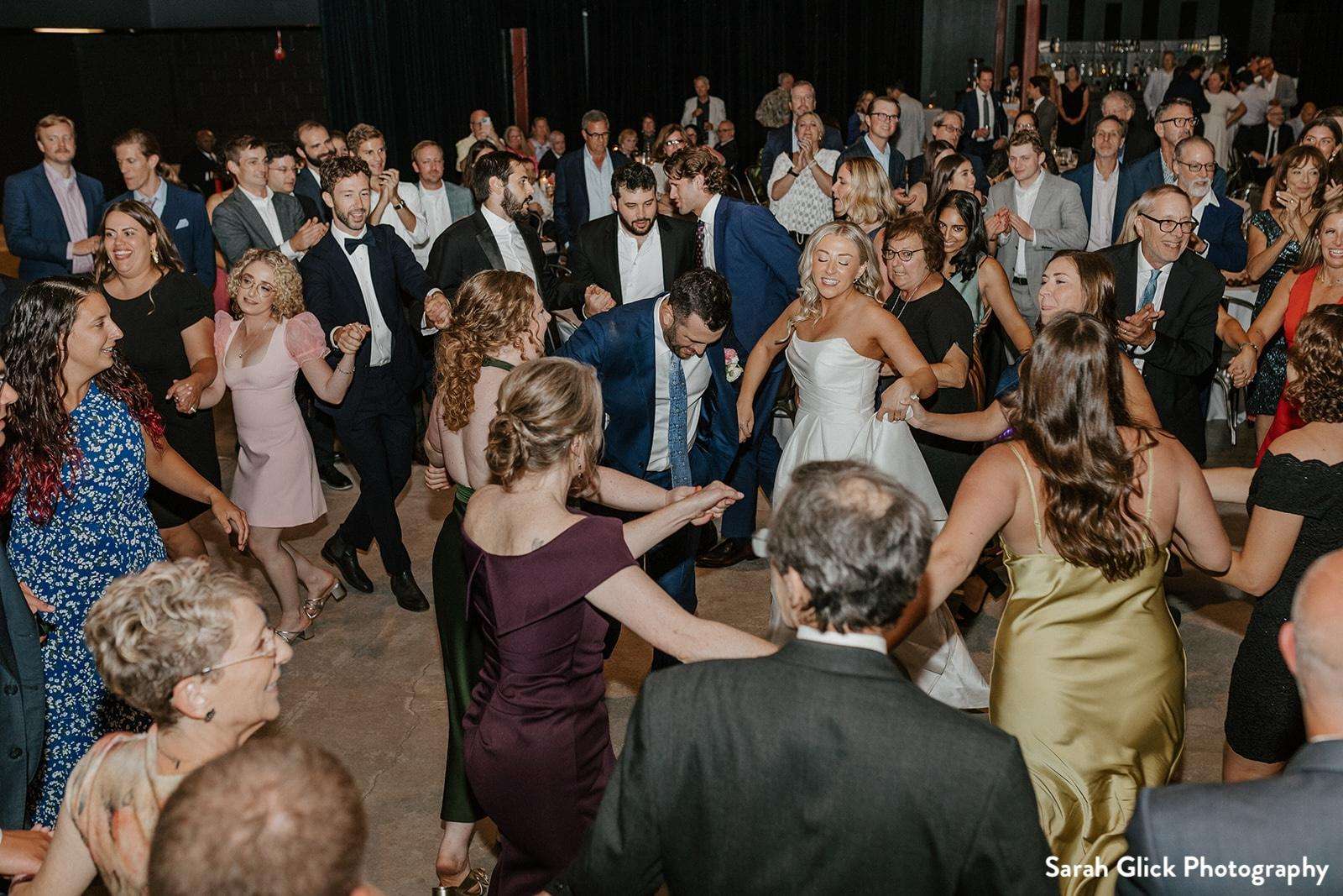 Guests join the couple on the dance floor at Jan Serr Studio, creating a lively atmosphere filled with smiles and celebration.