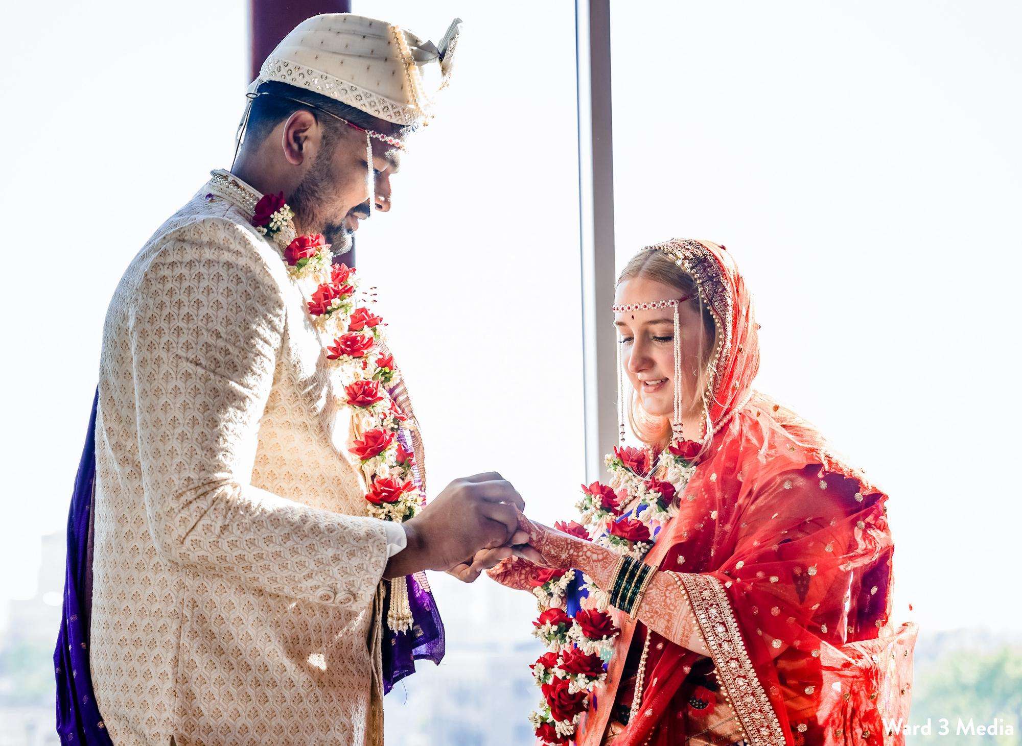 A groom and bride perform a traditional Indian wedding ceremony with vibrant floral garlands at Jan Serr Studio.
