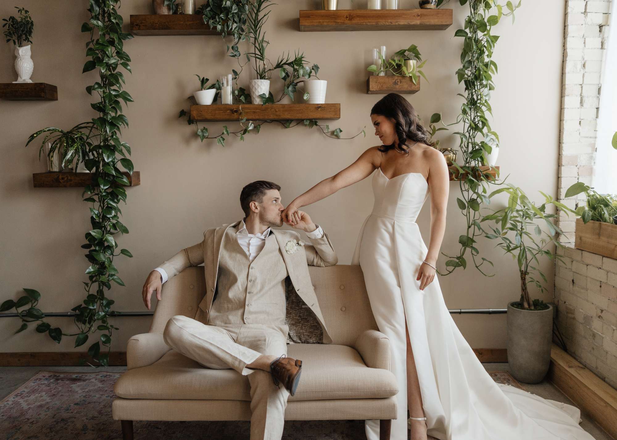 filament-milwaukee-ValerieHallingPhotography-6562 Newlyweds share a quiet moment in Filament's cozy lounge area, surrounded by lush greenery and modern decor.