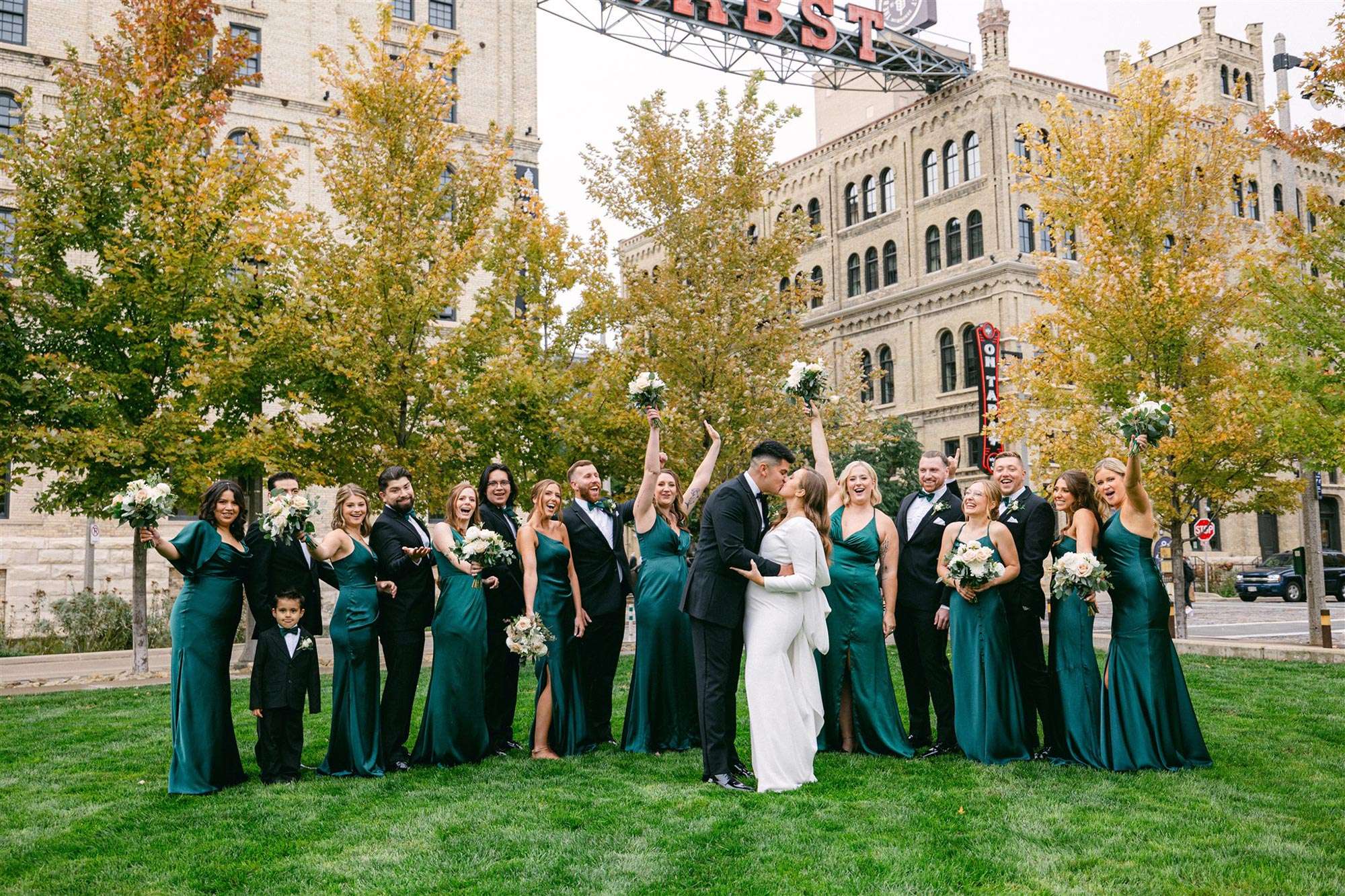 Wedding party cheering as couple share a kiss under the Pabst Brewing sign at Pilot Project Brewing Best Place at Historic Pabst Brewery
