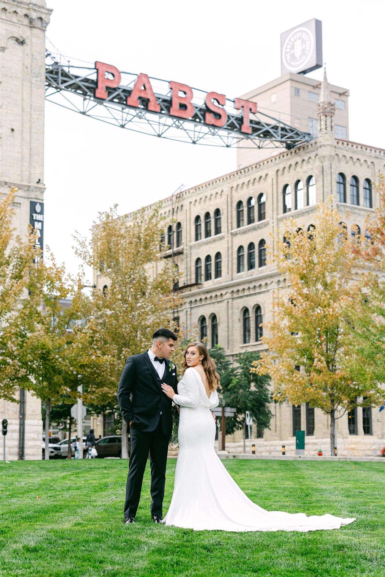 couple under PABST sign, bride showing back drape on wedding gown
