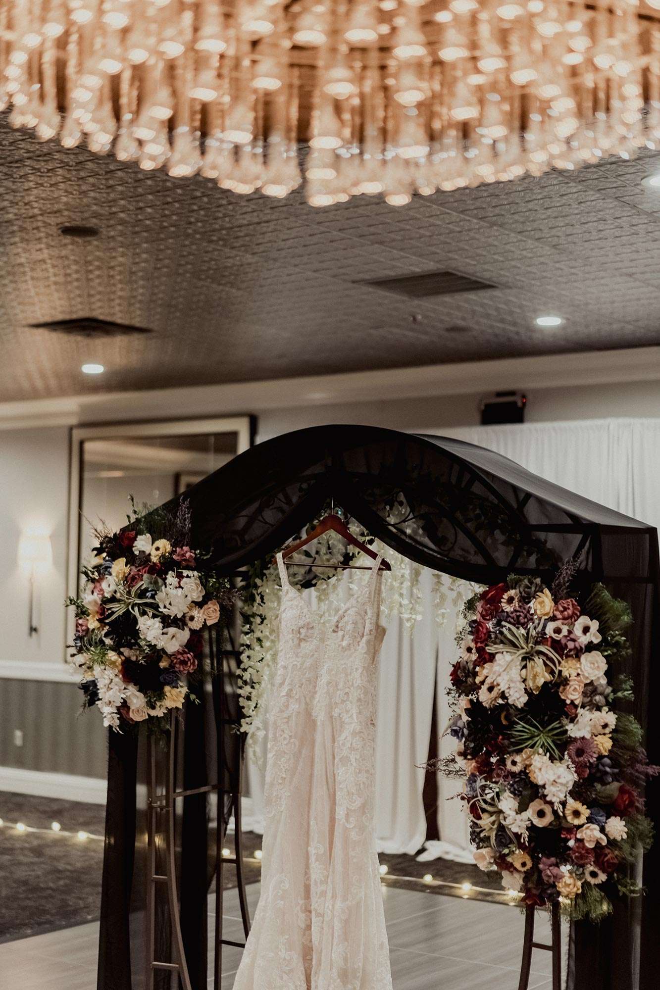 crystal chandelier at Delafield Hotel above ceremony arch with ivory,, lace detailed dress from Amelishan