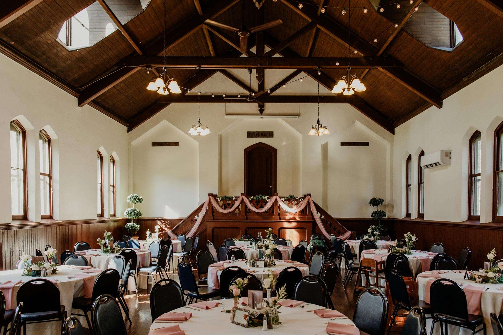 reception tables set with white tableclothes and pink linen napkins in The DeKoven Center Assembly Hall
