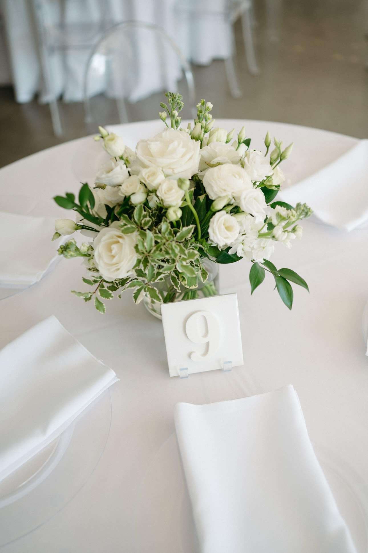 white floral centerpieces by Reflections of You provide light and airy touches on white linen table