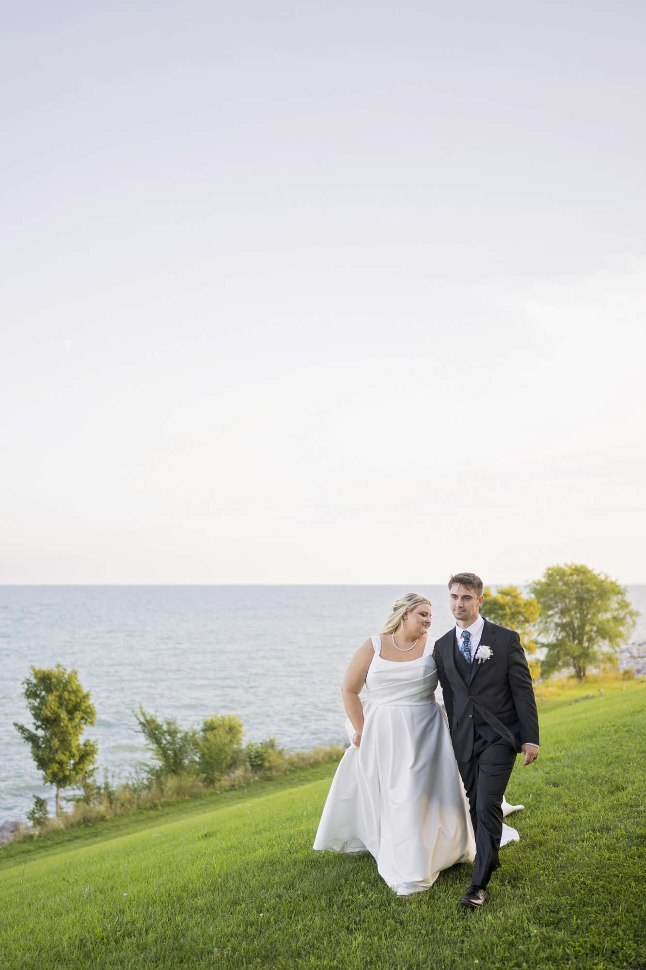 Bride and groom walking hand in hand on the lakefront of Lake Michigan in front of the Dekoven Center. Bride and groom walking hand in hand on the lakefront of Lake Michigan in front of the Dekoven Center.