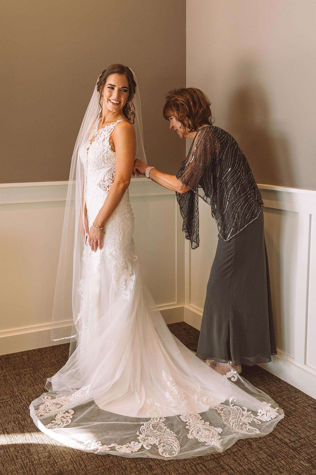 Mother of the bride fastening buttons on back of dress from Eva’s Bridal Center Eva’s Bridal Center