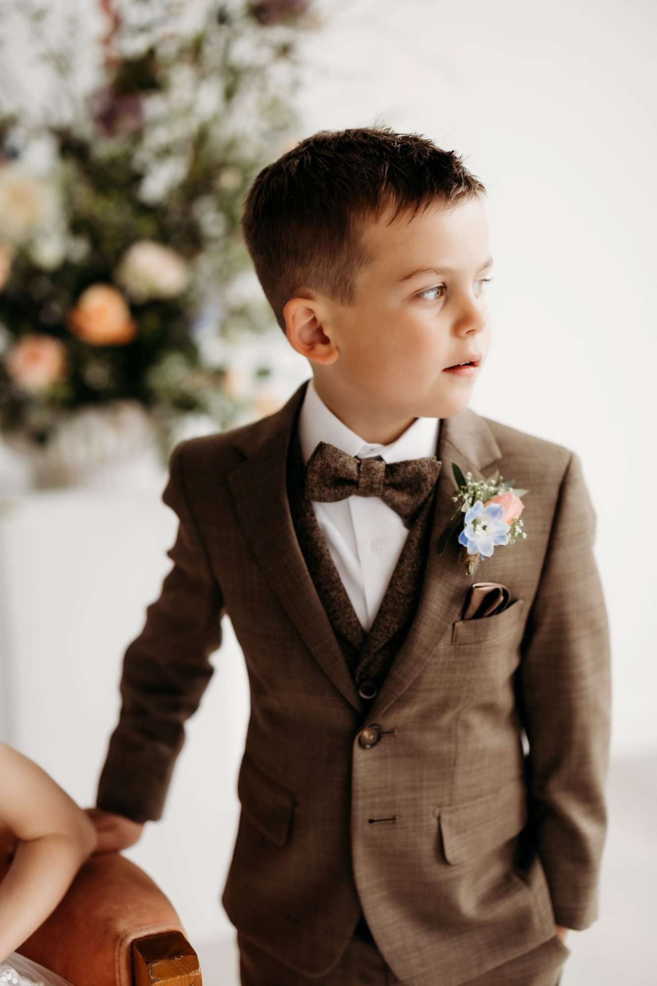 Young boy in dark brown tuxedo looking to the side as his picture is taken. Young boy in dark brown tuxedo looking to the side as his picture is taken.