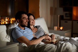 Couple sitting watching movie wit the movie date gift basket they received.