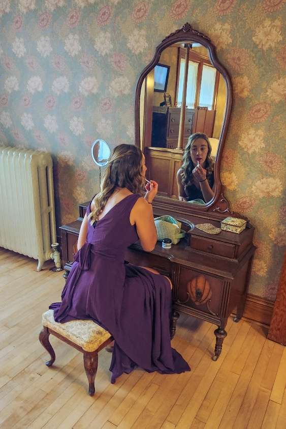 bridesmaid in purple dress applying lipstick in bridal suite room of the Schwartz Family House
