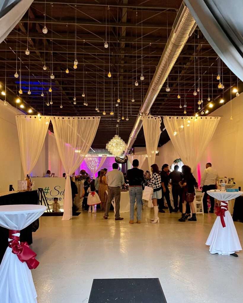 Elegant entryway at The Mitch, showcasing sheer drapery, chandeliers, and modern decor for an inviting event ambiance.
