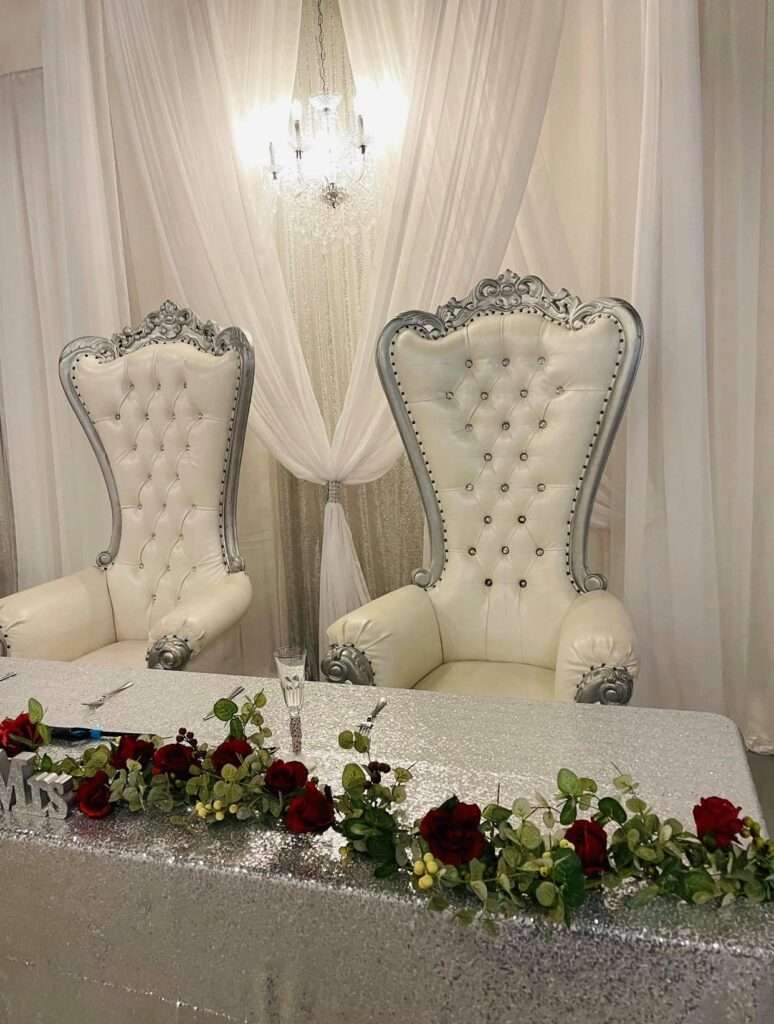 Regal sweetheart table setup at The Mitch, featuring throne chairs and romantic decor with shimmering accents.