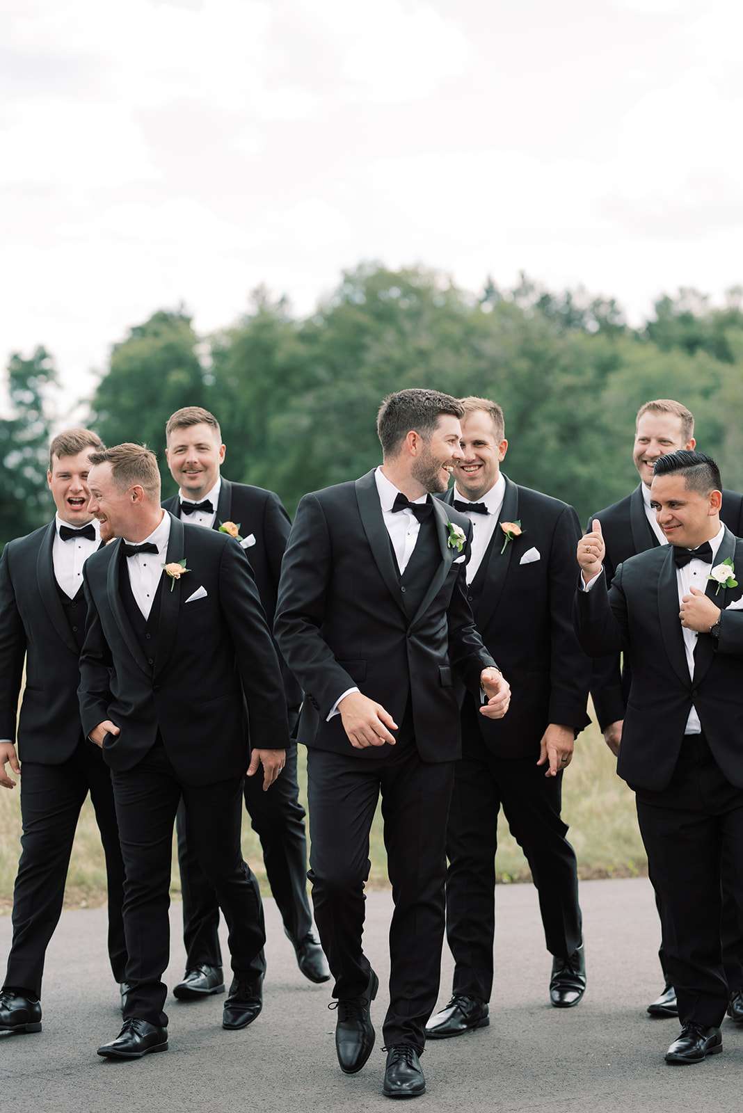 Groom and groomsmen in black tuxedos laughing together before wedding ceremony. Groom and groomsmen in black tuxedos laughing together before wedding ceremony.